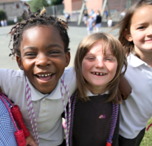 To unge piger i uniform efterligner tandbørstning med tandbørster lavet af pap